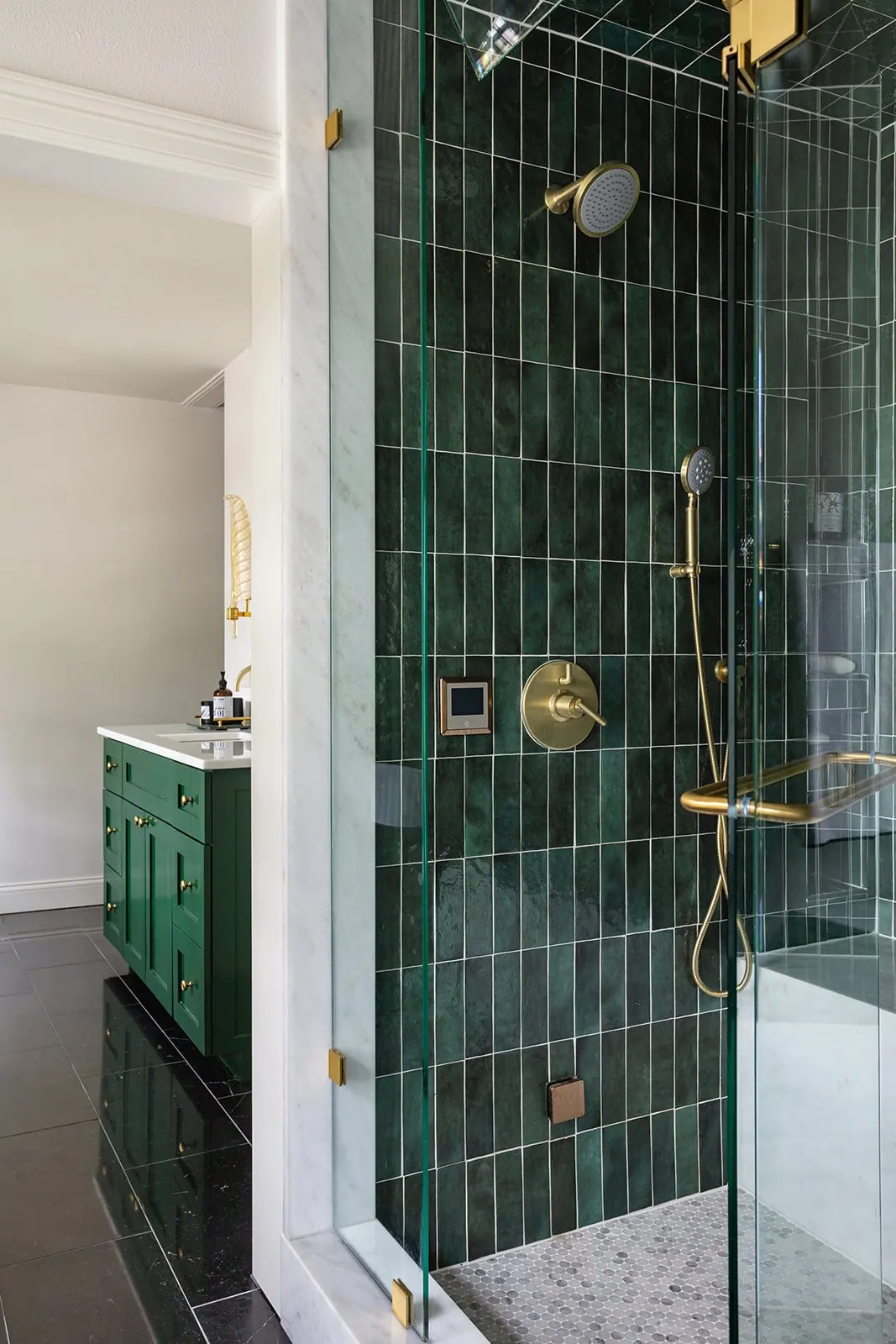 A green vertical tile walk-in shower with brass fixtures in a Tanglewood primary suite